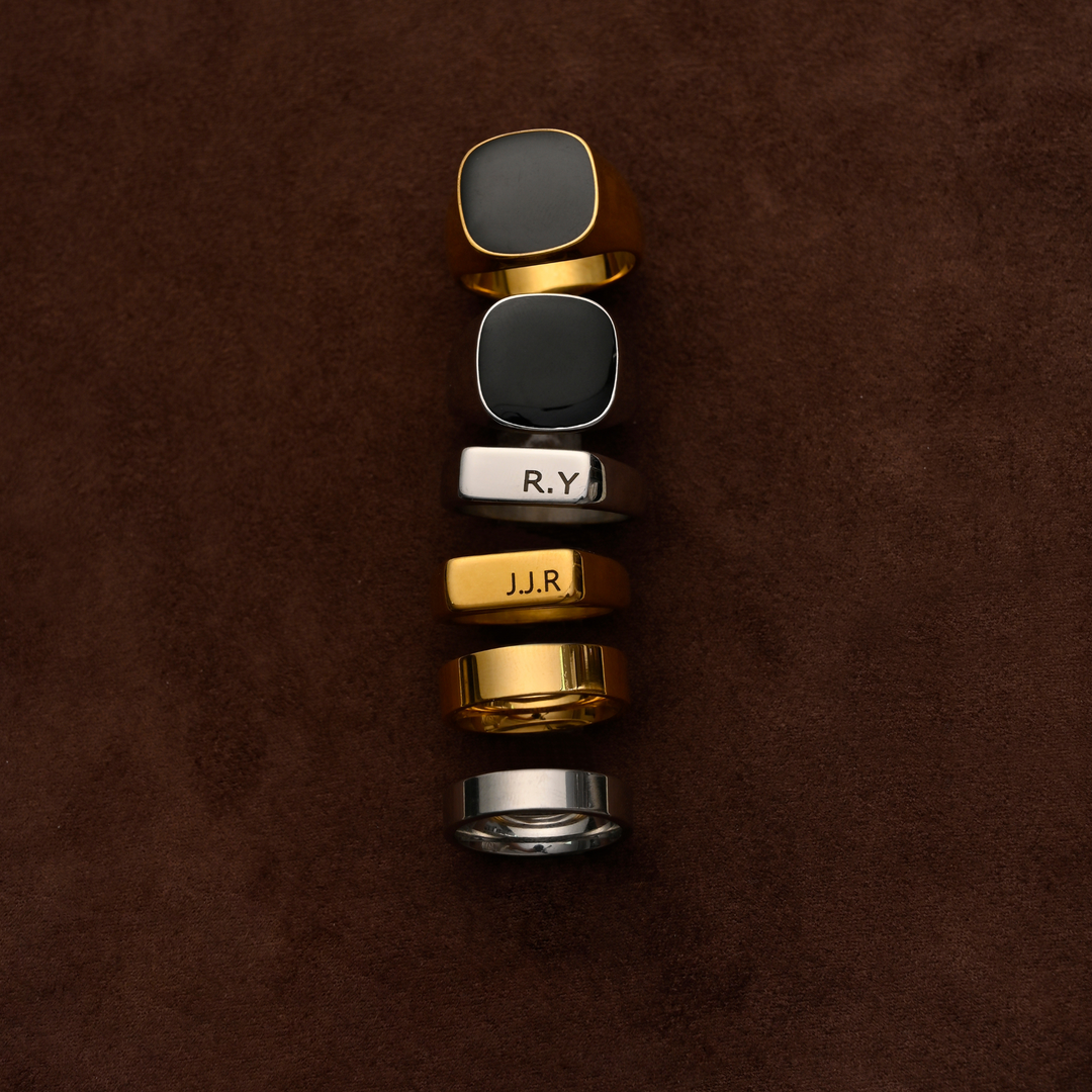 Set of five rings with engraved text on a brown textured background