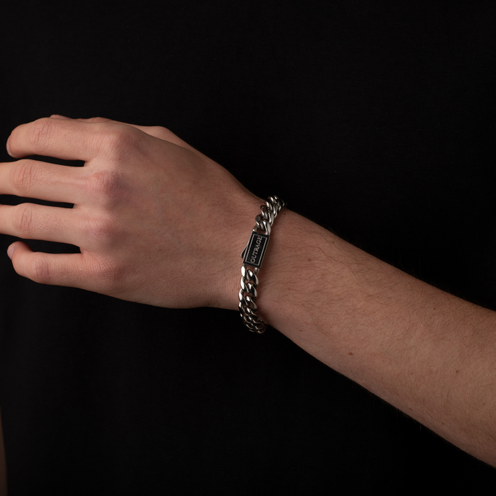 Hand wearing a silver chain bracelet on a black background