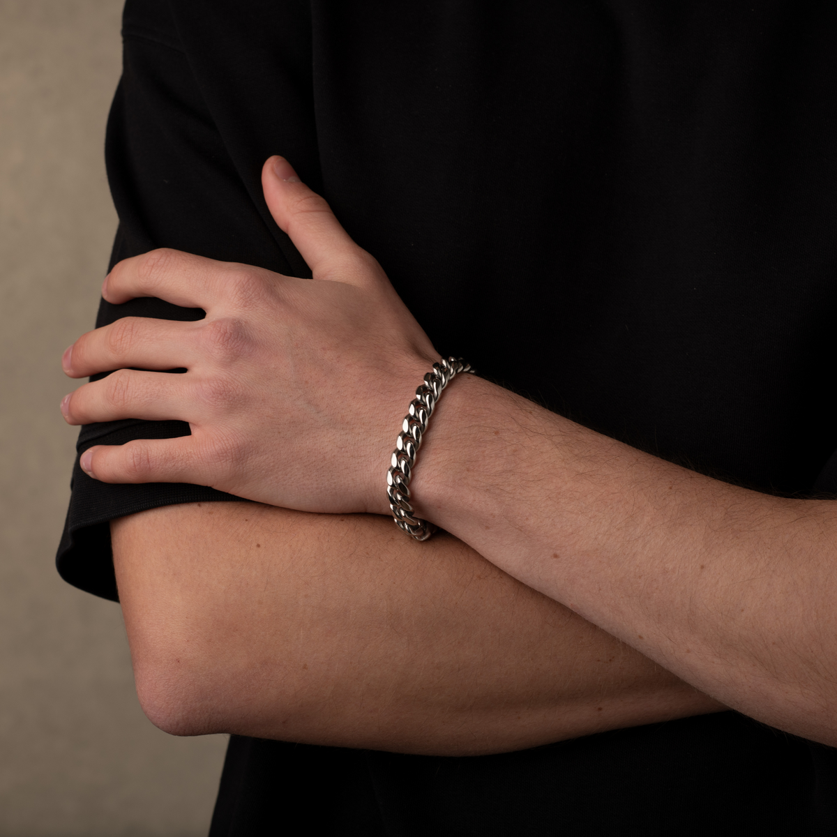 Person wearing a silver chain bracelet on a neutral background