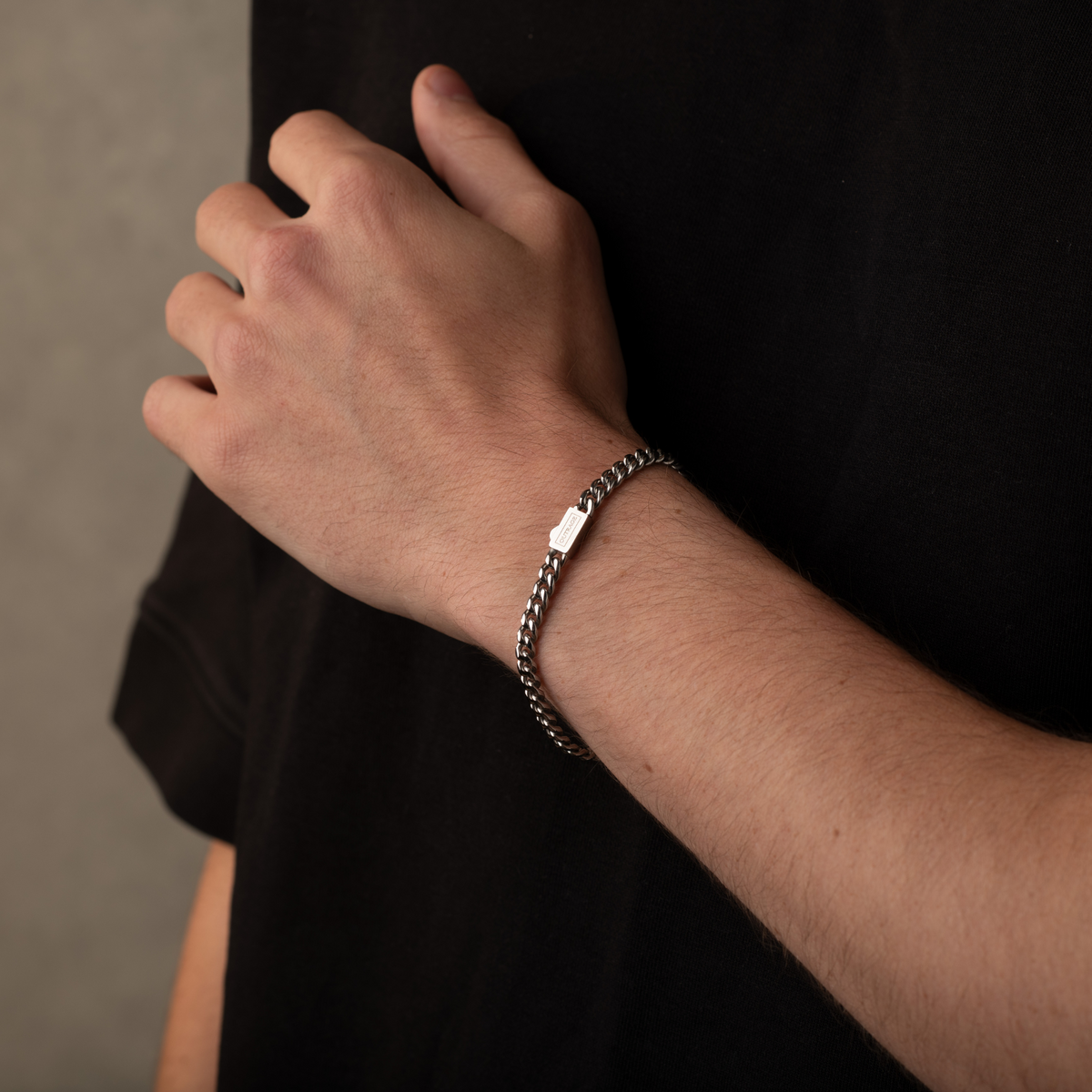 Hand wearing a chain bracelet on a dark background