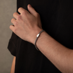 Hand wearing a chain bracelet on a dark background