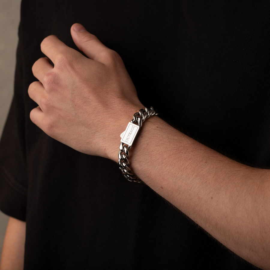 Hand wearing a silver chain bracelet on a plain background