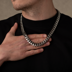 Person wearing a thick chain necklace with a neutral background