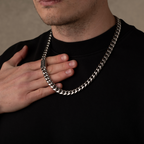 Man holding a silver chain necklace against a neutral background