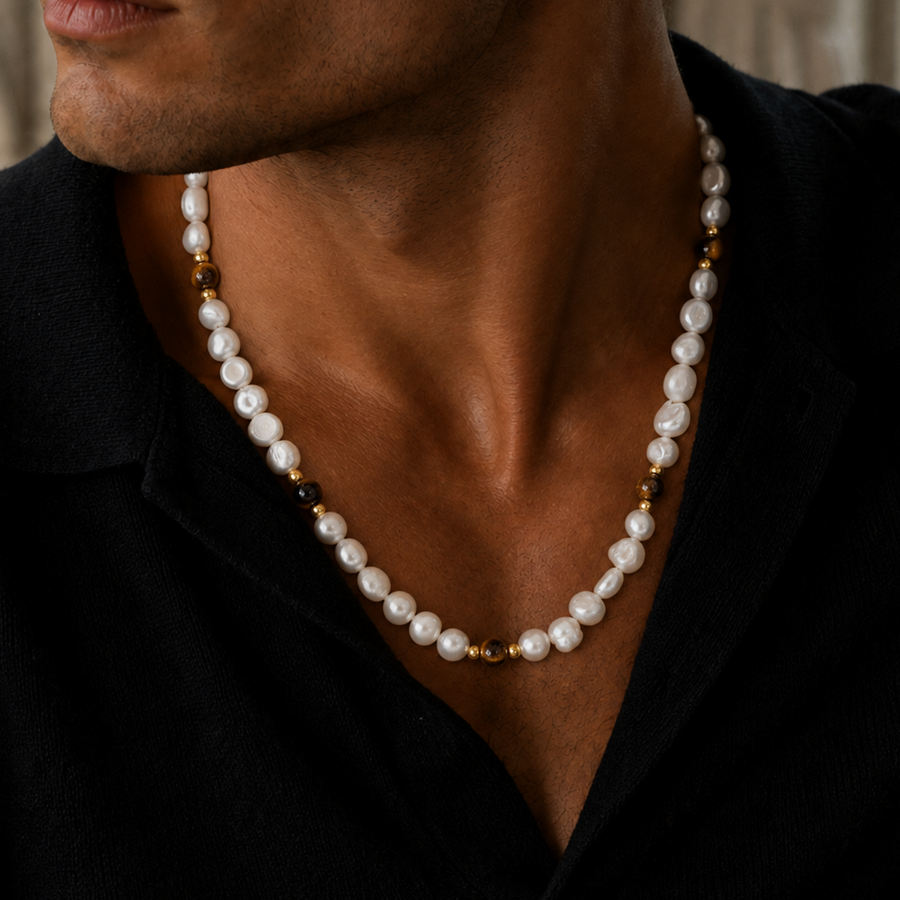 A close-up of a man wearing a white baroque pearl necklace with small gold spacer beads, styled with a black shirt.