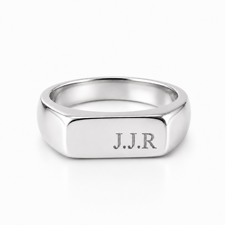 A silver-toned signet ring with a polished hexagonal face engraved with the initials 'J.J.R'