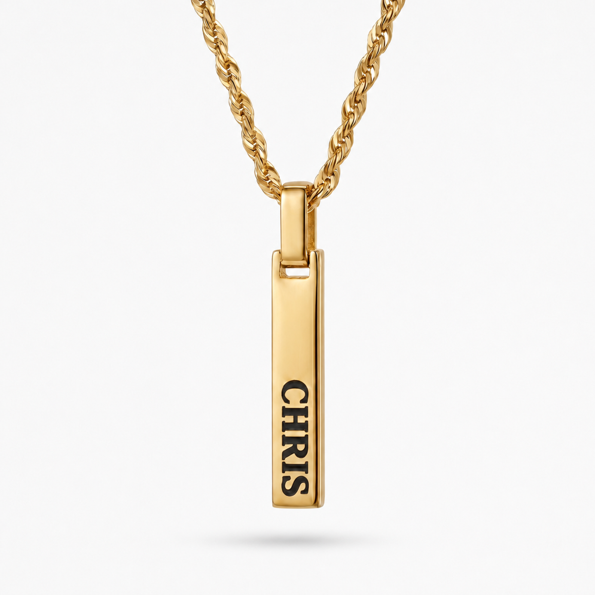 A gold-plated vertical bar pendant necklace engraved with the name 'CHRIS' in black capital letters, suspended from a matching gold rope chain against a light gray background.