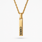 A gold-plated vertical bar pendant necklace engraved with the name 'CHRIS' in black capital letters, suspended from a matching gold rope chain against a light gray background.
